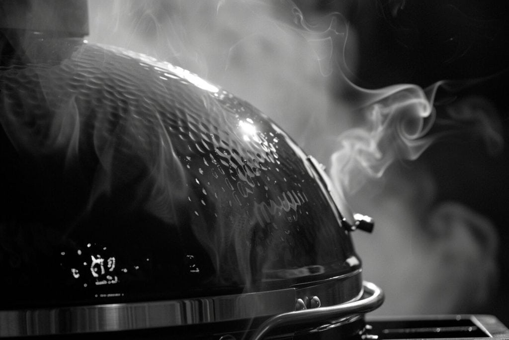 Smoke billowing out the top of a smoker.