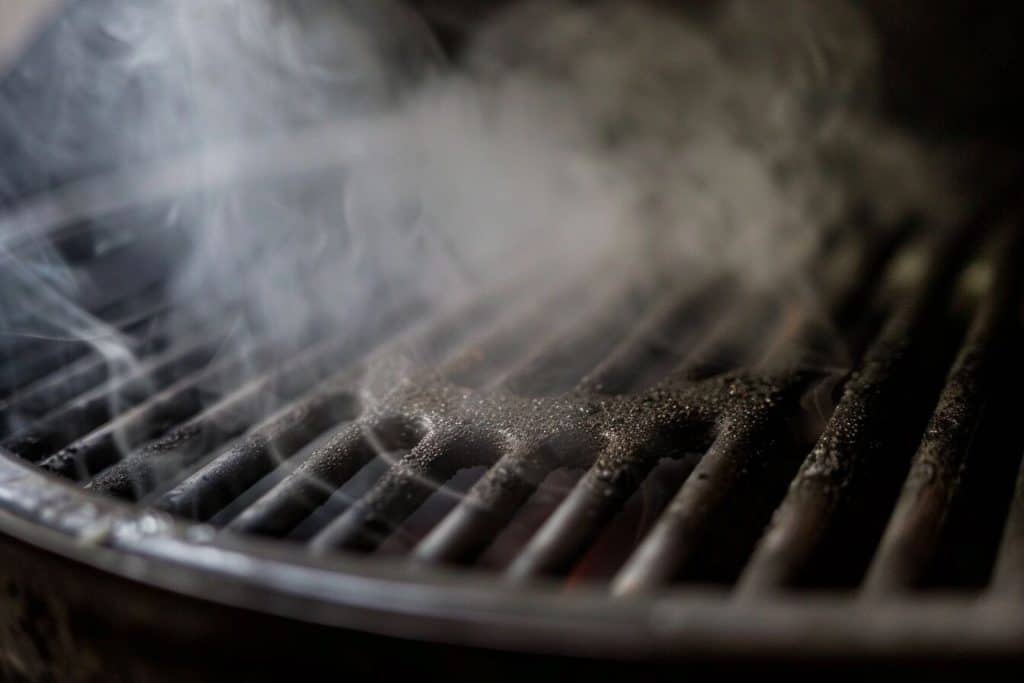 Smoke rising above the grill of a weber kettle.