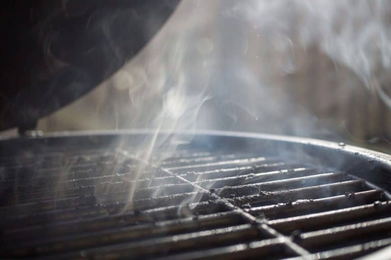 Close up of the grill grate on the Weber kettle grill. Smoke billowing up.