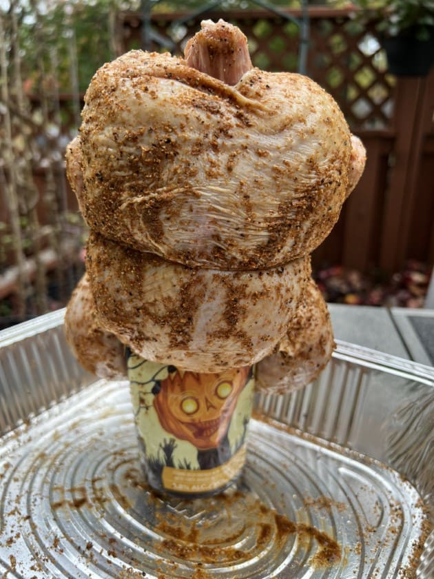 A chicken perched on a beer can.