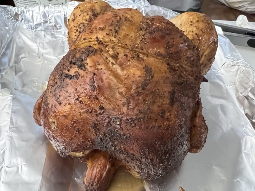 Beer can chicken resting on a foiled baking sheet.