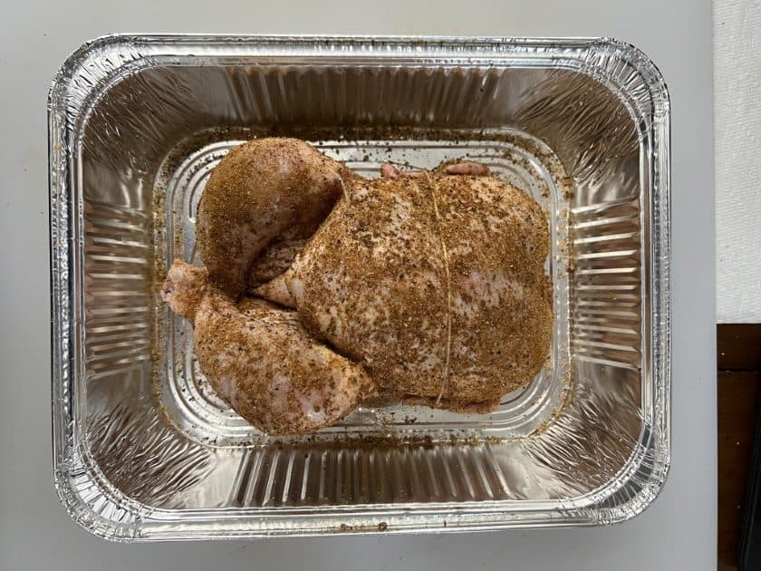 Chicken covered in Dizzy Pig Wonderbird rub in a foil pan.