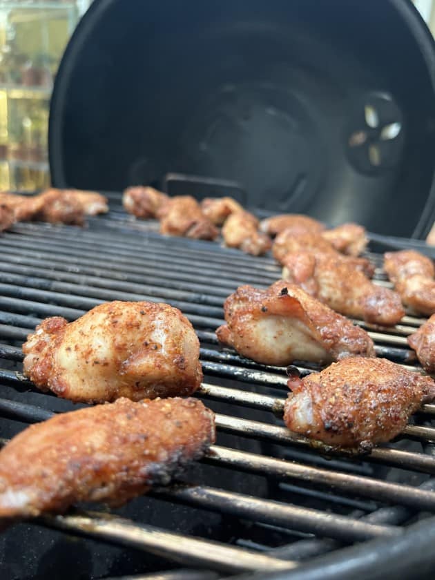 Close up of chicken wings on the grill grate of a Weber Kettle.