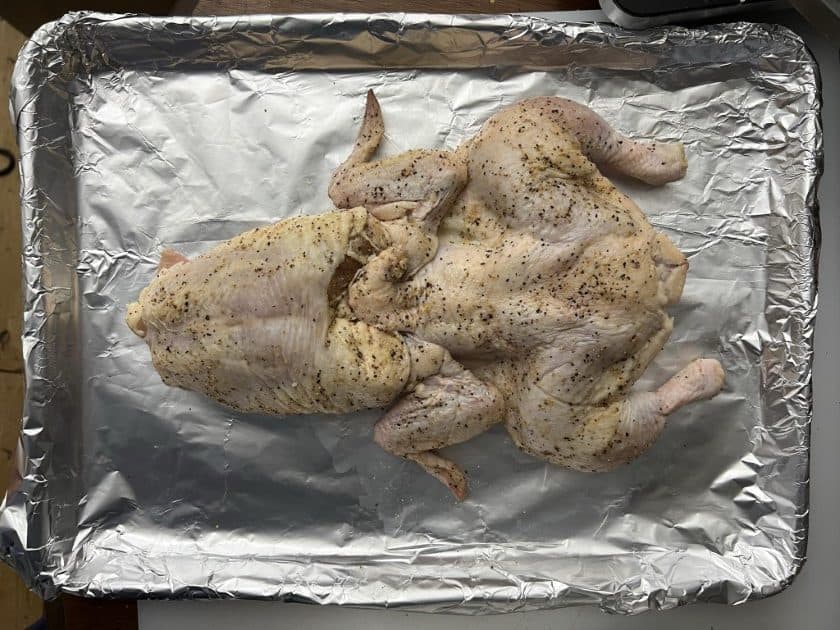 Bullfrog chicken being prepared on a foil covered baking sheet.