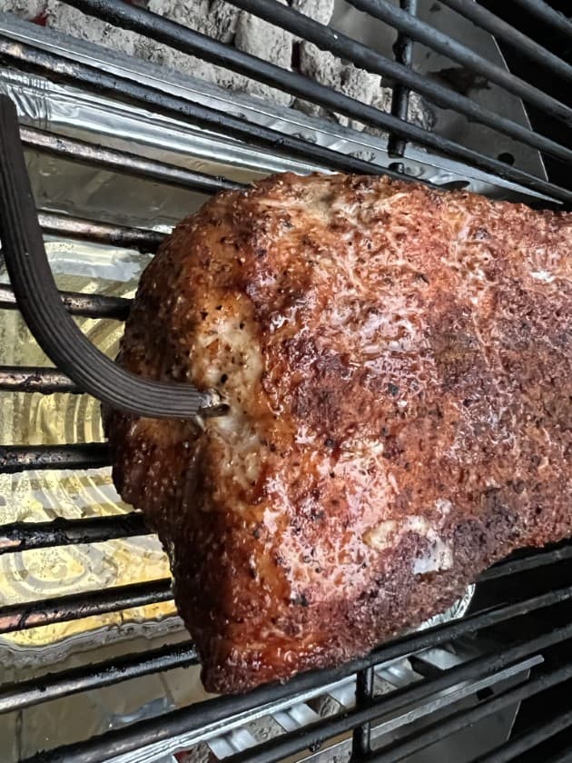 Meat probe sticking out of bbq pork loin on weber kettle.