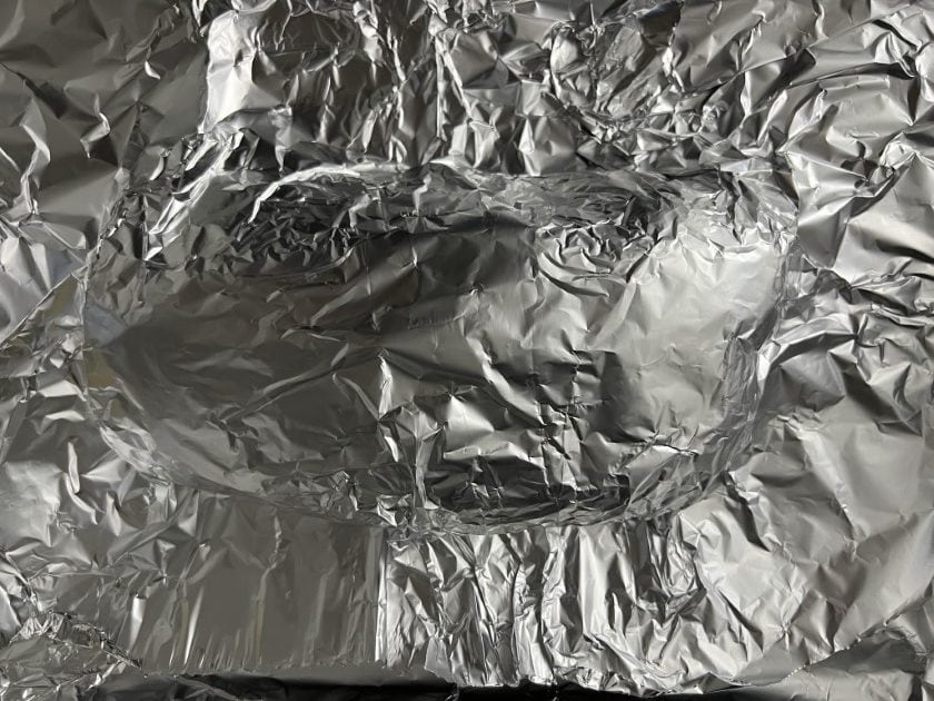 Pork loin wresting wrapped in aluminum foil.
