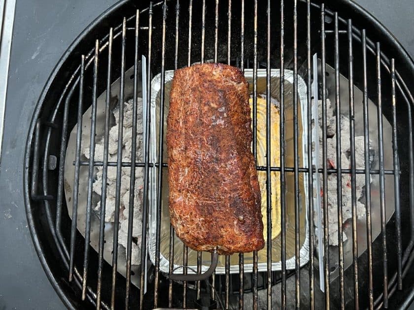 Pork loin smoking away on a Weber kettle grill.