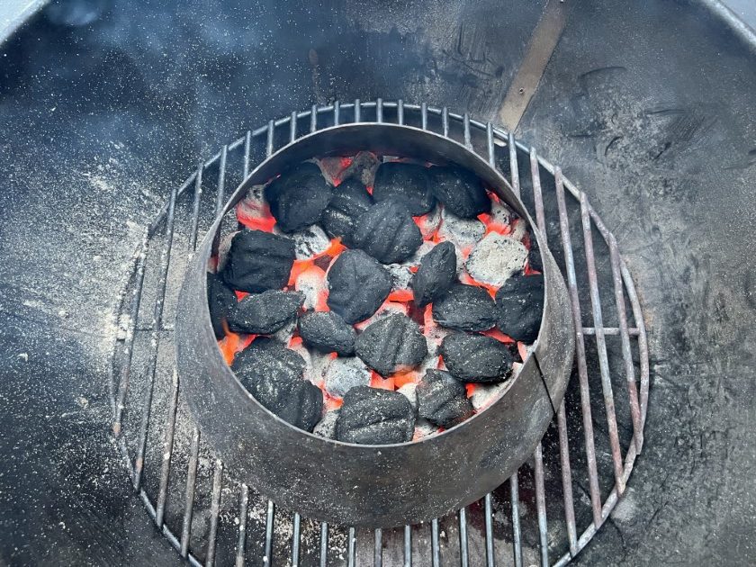 Vortex filled with hot coals in the middle of a weber kettle grill.