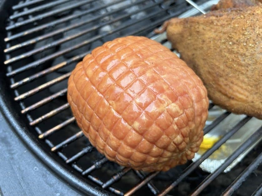 Whole boneless toupie ham on the grill grate of the Weber Kettle.
